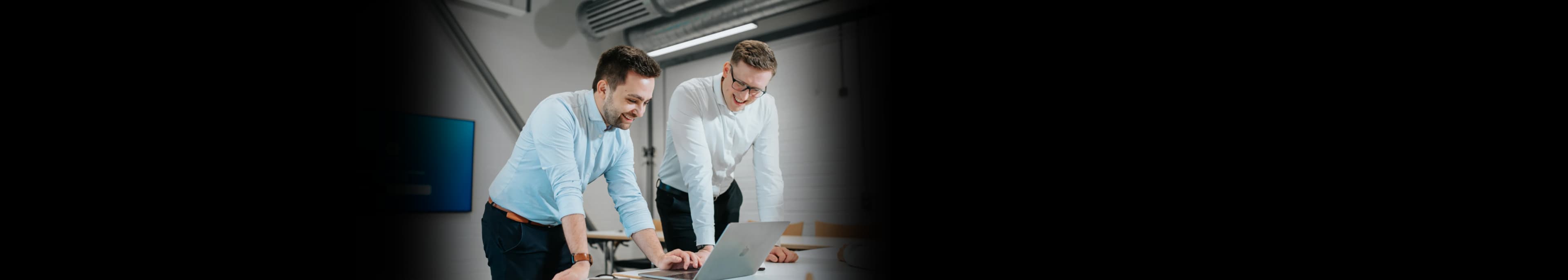 Working atmosphere at northcommit: IT consultants work on a software solution while looking at a MacBook.